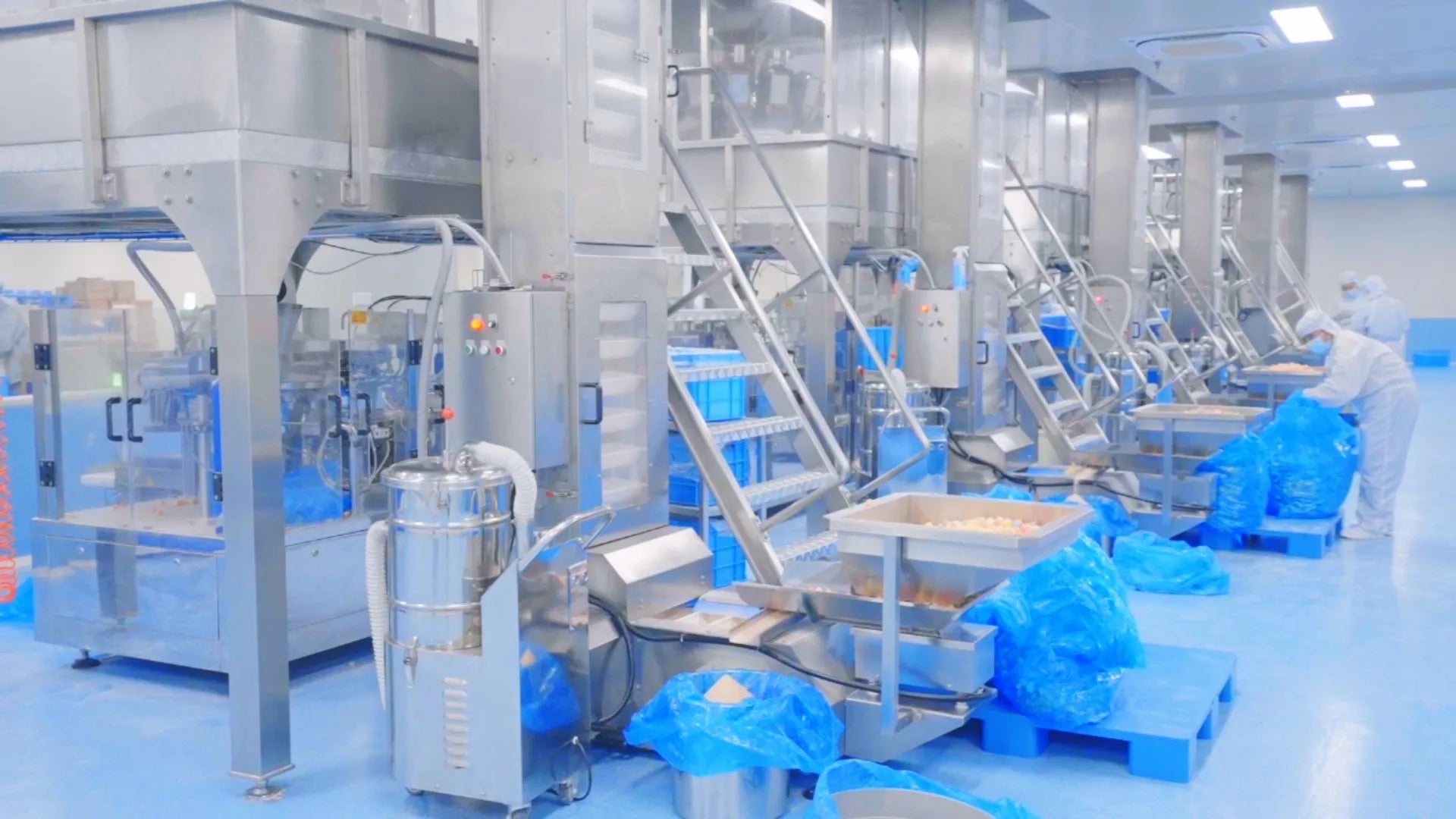 Row of packing lines with workers in white cleanroom suits